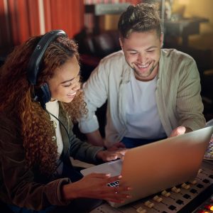 Dos jóvenes miran la pantalla de un portátil, en un estudio de producción